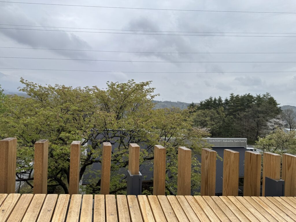 白州蒸溜所の集合場所へ向かう橋から見た新緑の木々と建物